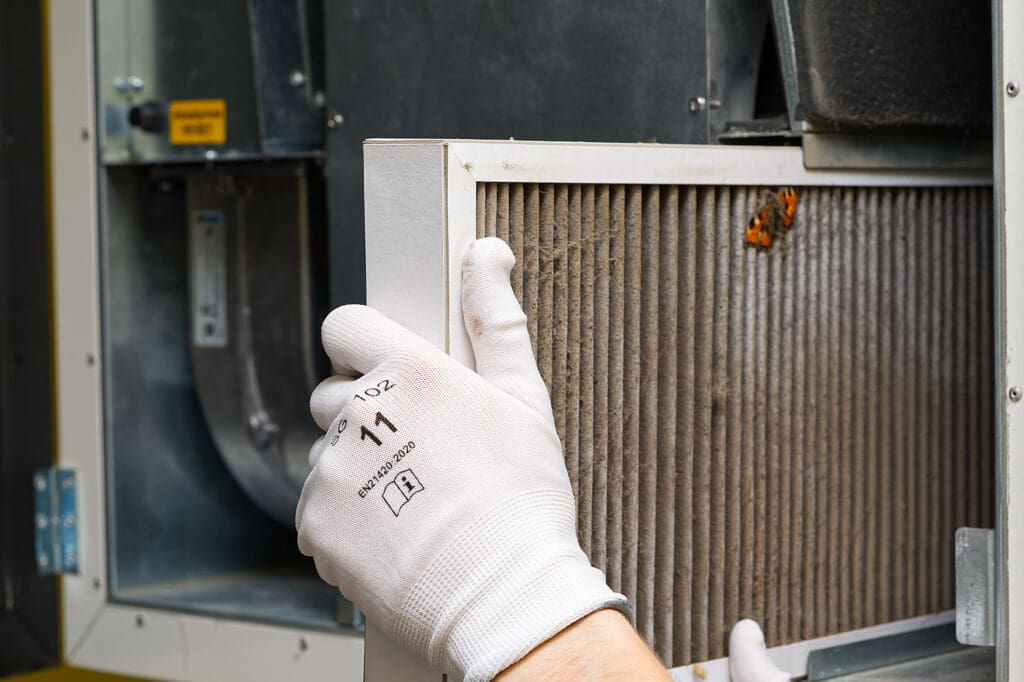 Looking at a dirty air filter in a HVAC system to demonstrate why its important to change the air filter in home HVAC systems regularly.